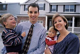A young couple with a baby standing in front of their NJ home.